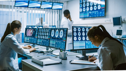 Team of Professional Scientists Work in the Brain Research Laboratory. Neurologists / Neuroscientists Surrounded by Monitors Showing CT, MRI Scans Having Discussions and Working on Personal Computers. - Powered by Adobe