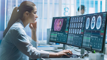 Female Medical Research Scientist Working with Brain Scans on Her Personal Computer. Modern...