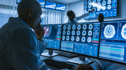 Over the Shoulder Shot of Senior Medical Scientist Working with CT Brain Scan Images on a Personal...