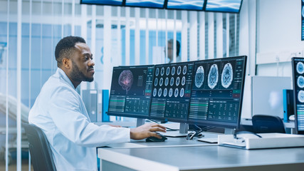 Medical Scientist Working with CT Brain Scan Images on a Personal Computer in Laboratory. Neurologists in Neurological Research Center Working on a Brain Tumor Cure.