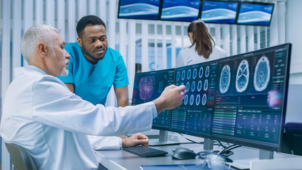Medical Scientist and Surgeon Discussing CT / MRI Brain Scan Images on a Personal Computer in...