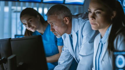 Diverse Team of Medical Scientists Solve Problems and Point at Computer Screens Showing CT, MRI...