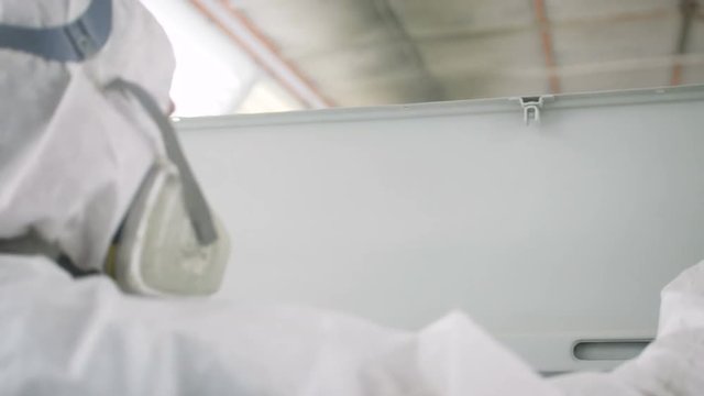 backside view worker in mask paints lorry body with sprayer
