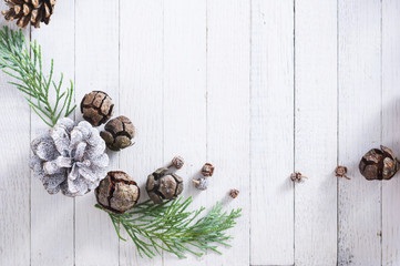 Christmas decoration background: pine and cypress cones with twigs on white wood table