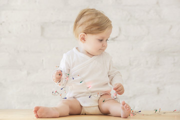 Fototapeta premium Adorable blonde baby playing with Christmas tree lights