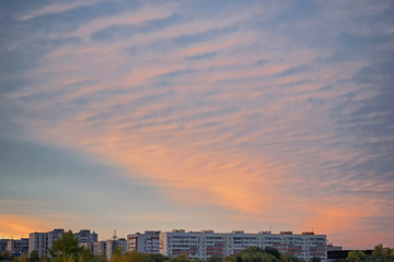 Beautiful cloudy sky at sunset over the houses in evening city