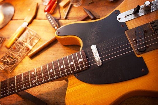 Guitar on repair desk. Vintage electric guitar on a repair work shop. Single cutaway electric guitar, amber color.