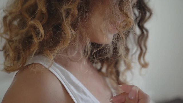 Young cheerful curly woman sitting on the bed and laughing. in the background sits a sad man. 4K