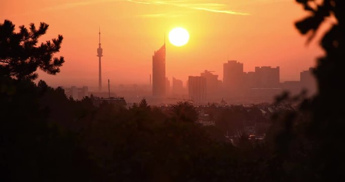 Time-lapse of sunrise over Donaucity in Vienna seen from the outskirts. Sunshine dives famous skyscrapers in dazzling bright light, showing only the silhouettes of the skyline.