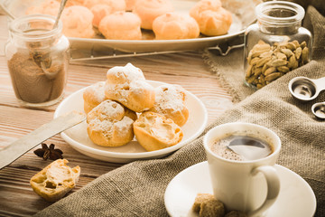 Espresso in a white coffee cup served with homemade profiteroles on a wooden table.