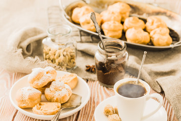 Espresso in a white coffee cup served with homemade profiteroles on a wooden table.
