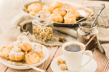 Espresso in a white coffee cup served with homemade profiteroles on a wooden table.
