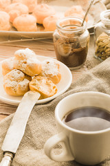 Cup of black tea with home made profiteroles on a rustic wooden table.