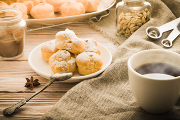 Cup of black tea with home made profiteroles on a rustic wooden table.