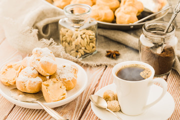 Espresso in a white coffee cup served with homemade profiteroles on a wooden table.