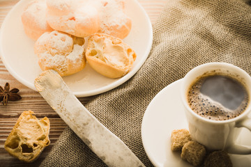 Espresso in a white coffee cup served with homemade profiteroles on a wooden table.
