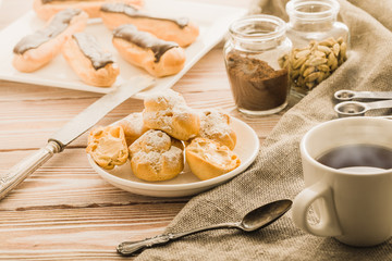 Cup of black tea with home made profiteroles on a rustic wooden table.