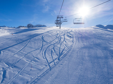 Ski lift and ski slope with skiers under it on sunny winter day with blue sky. Alpine resort Courchevel, France. January, 2018