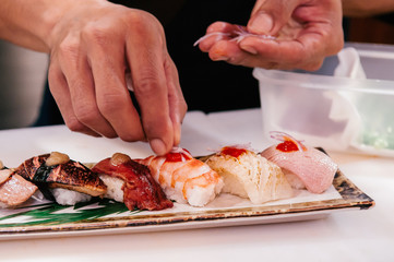 Chef put sliced onion on many kind of Japanese Sushi on ceramic plate