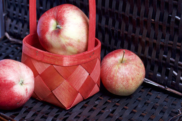 Ripe aromatic apples on the background of a wicker basket of vines.