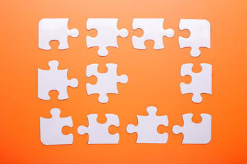 White puzzle on orange background. Missing piece. Top view