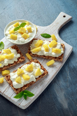 Homemade Crispbread toast with Cottage Cheese and Pineapple on white wooden board.