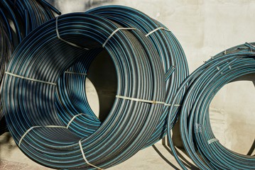 Fototapeta premium hanks of black plastic pipes stand on the gray wall of the building on the street