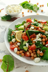 Chickpeas Salad with cucumber, tomatoes, feta cheese and green mix in a white plate. healthy food.