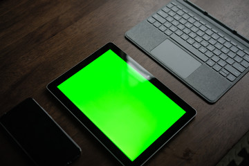 A Computer Tablet and ultra-slim smartphone with green screen/chroma key on brown table