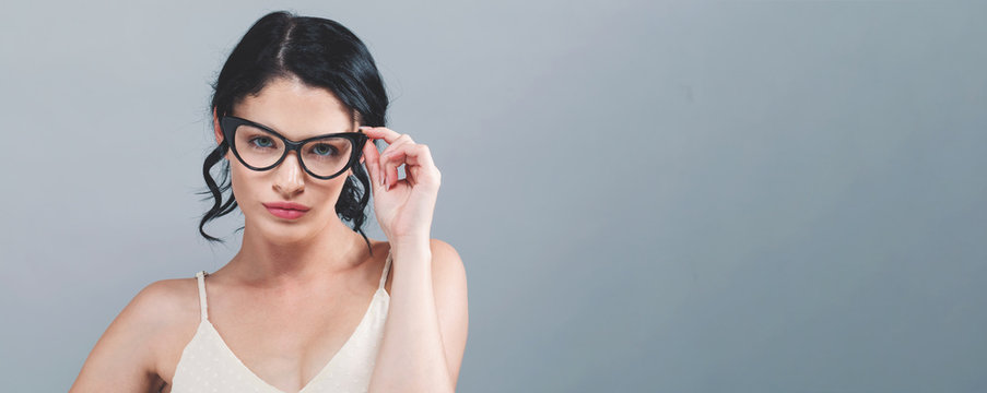 Young Woman With Eye Glasses On A Gray Background