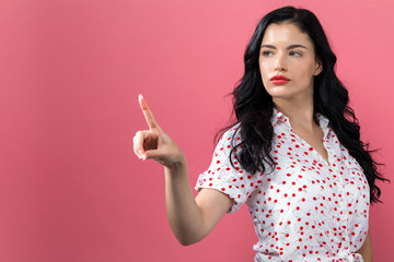 Young woman pointing at something on a solid background