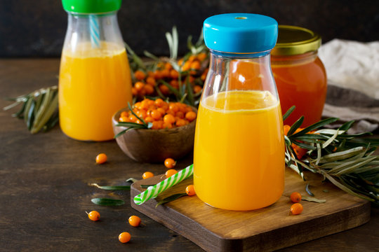 Sweet drink juice with fresh sea buckthorn on a rustic background. Copy space.