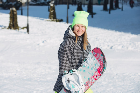 Woman carrying her snowboard on snowy slope