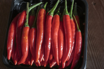 Pods of red chili peppers, in the black pallet, isolated on white background.
