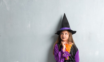 Little girl dressed as a witch for halloween holidays and thinking