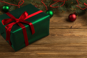 Green gift with red ribbon, Christmas tree and decorations on the table. New year.