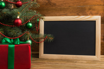 Green red gifts and chalkboard under the tree, on the table, against the wood background. The concept of Christmas and New Year.