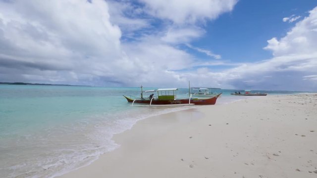 Ultra slow motion shot of traditional filipino bangka boat in red anchored on gorgeous beach