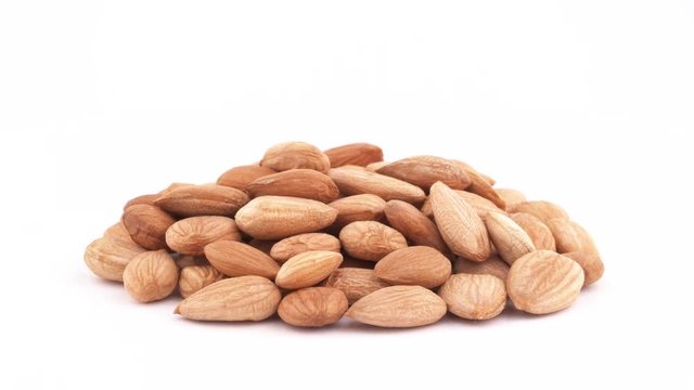 A pile of apricot kernels heap. Smoothly rotating on the turntable, isolated on the white background. Close-up. Macro.
