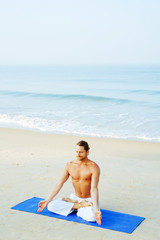 Athletic Man on Mat doing Yoga at the Beach