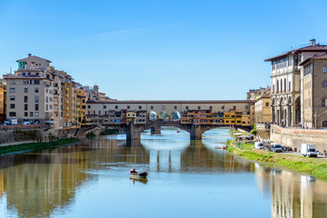 Fototapeta na wymiar Panoramic view of the Ponte Vecchio bridge over Arno river in Florence, Italy with a view of a traditional boat during sunset.