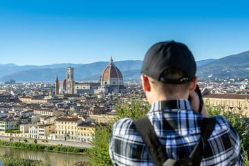 A tourist taking a panoramic photo of Florence, Italy before sunset with the view of Arno river and the famous Cathedral Santa Maria del Fiore and the Duomo.