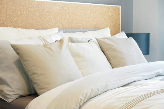 Closeup row of pillows on bed, beige color scheme bedding