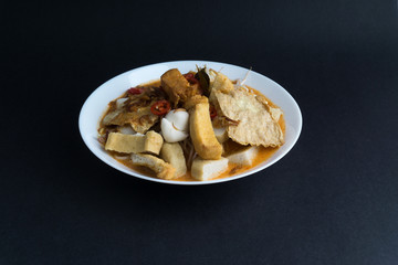 Curry noodles in a plate on dark background with selective focus and crop fragment