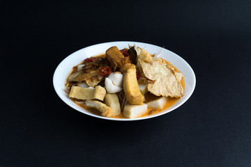 Curry noodles in a plate on dark background with selective focus and crop fragment