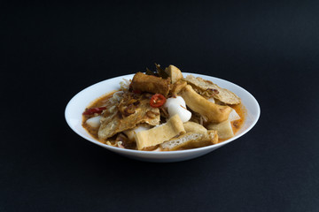 Curry noodles in a plate on dark background with selective focus and crop fragment