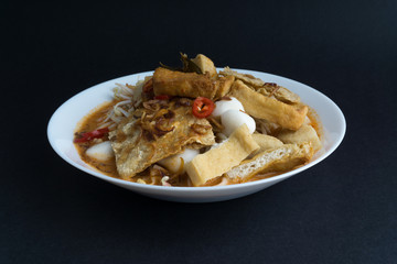Curry noodles in a plate on dark background with selective focus and crop fragment