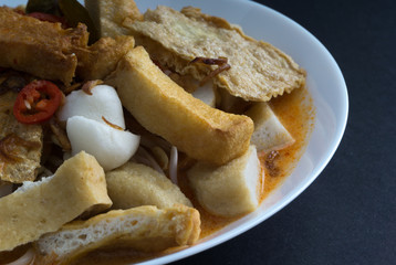 Curry noodles in a plate on dark background with selective focus and crop fragment