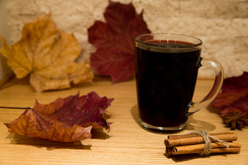 Red mulled wine with orange, cinnamon rolls, cloves, walnuts and anise stars. Brick wall background.