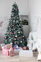 Christmas tree in a white room decorated with pink, gold and silver jewelry balls